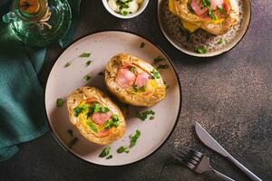 Baked whole potatoes with egg, sausages and herbs on a plate top view photo