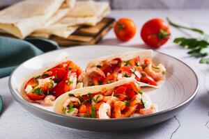 Vegetarian mini tacos with tomatoes, shrimp and herbs on a plate on the table photo