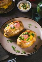 Baked potatoes in skins with egg and pieces of sausage on a plate on the table vertical view photo