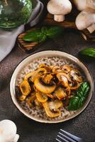 Savory appetizer of fried champignon mushrooms with basil on a plate on the table vertical view photo