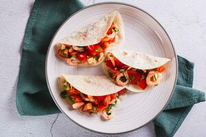 Close up of vegetarian mini tacos with tomatoes, shrimp and herbs on a plate top view photo