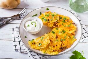 Traditional potato latkes with greens and sauce on a plate on the table photo