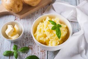 Bowl with delicious homemade mashed potatoes and basil on the table photo