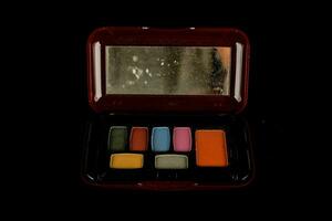 a small box with a mirror and a variety of colored eyeshadows photo