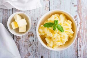 Close up of fresh mashed potatoes and basil leaves in a bowl on the table top view photo