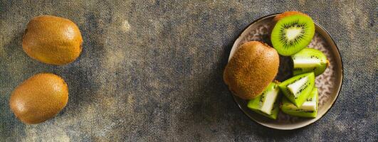 Ripe sliced kiwi fruit and whole on a plate on the table top view web banner photo