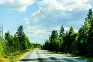 a long empty road surrounded by trees and clouds photo