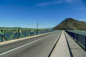 a bridge over a river with a mountain in the background photo