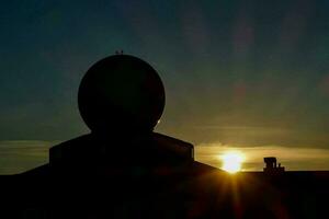 the sun is setting behind a dome on top of a building photo