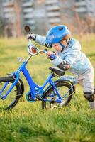 linda niño es conducción un bicicleta en un soleado día a puesta de sol foto