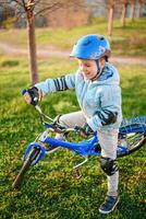A child in a helmet learns to ride a bike on a sunny day at sunset photo