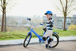 Cute child in helmet and protection stands near his bike photo