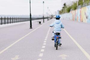 A child in a helmet and protection in a bike ride on nature in the spring photo