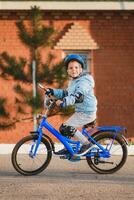 pequeño chico en casco paseos un bicicleta en un soleado día foto