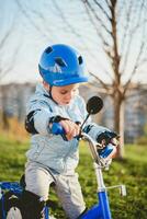 pequeño chico en casco paseos un bicicleta en un soleado día foto