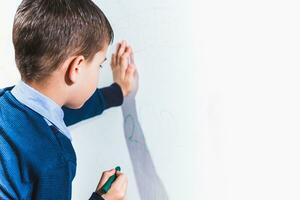 Cute child draws on the wall with colored crayons photo