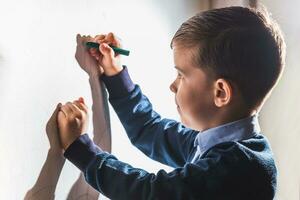 el niño sorteos en el pared con un lápiz de color. el chico es comprometido en creatividad a hogar foto