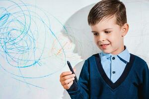 The child draws on the wall with a crayon. The boy is engaged in creativity at home photo