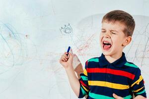 gritando niño sorteos en el pared con de colores lapices foto