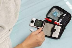 A woman's hand checking her blood sugar level with a glucometer by herself at her home. SHOTLISThealth photo