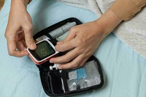 A woman's hand checking her blood sugar level with a glucometer by herself at her home. SHOTLISThealth photo