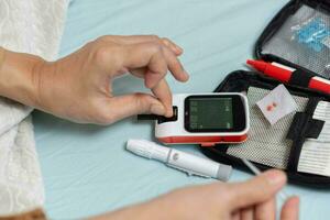 A woman's hand checking her blood sugar level with a glucometer by herself at her home. SHOTLISThealth photo