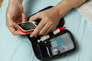 A woman's hand checking her blood sugar level with a glucometer by herself at her home. SHOTLISThealth photo