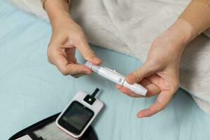 A woman's hand checking her blood sugar level with a glucometer by herself at her home. SHOTLISThealth photo