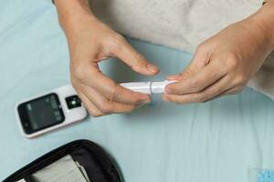 A woman's hand checking her blood sugar level with a glucometer by herself at her home. SHOTLISThealth photo