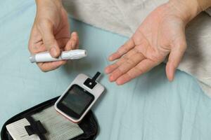 A woman's hand checking her blood sugar level with a glucometer by herself at her home. SHOTLISThealth photo