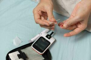 A woman's hand checking her blood sugar level with a glucometer by herself at her home. SHOTLISThealth photo