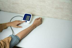 Young woman measuring his blood pressure at home. self blood pressure and heart rate photo