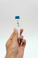 Female hands holding a digital thermometer. Girl measures the temperature. Fever and healthcare concept photo