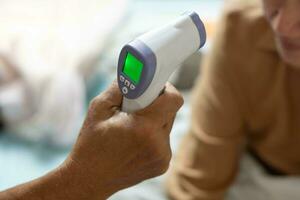 middle age woman being checked with her husband for temperature at home photo