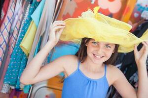 Cute Blue Eyed Girl Playfully Modeling a Big Sun Hat at the Market. photo