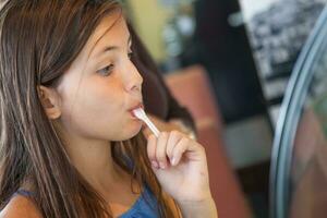 linda joven niña muestreo un gusto de helado a el hielo crema tienda. foto