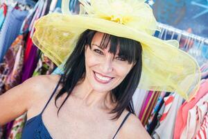 sonriente morena mujer modelado un grande Dom sombrero a el mercado. foto