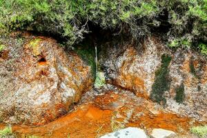 un corriente de rojo agua fluye mediante un agujero en el suelo foto