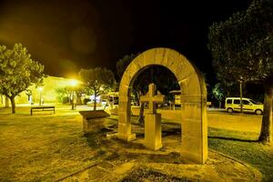 a stone archway in the middle of a park at night photo