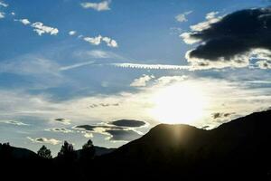 the sun is setting behind a mountain range photo