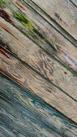 Background of textured wooden surface made of boards with multicolored spots from humidity, diagonal lines, top view, closeup. photo