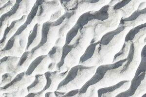 Gray texture background of Pamukkale calcium travertine in Turkey, pattern of diagonal waves, closeup. photo