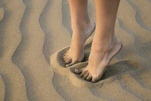 Detail of female legs on golden sea sand of the beach close up. photo