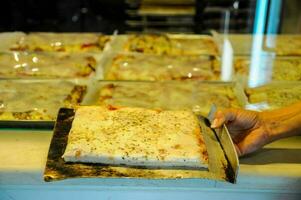 a person holding a tray of pizza in front of a counter photo