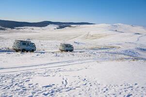 Russian Off-road vans driving on the snowfield in Olkhon island for carrying tourist to visit Baikal lake the world's deepest lake located in southern Siberia, Russia. photo