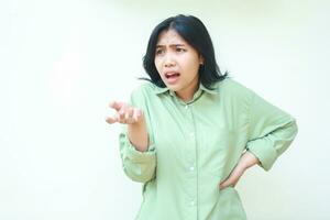 studio shot of clueless asian woman standing over isolated white background with raising palms and hands on waist looking away show questioning gesture and mad expression photo