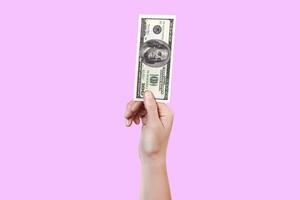 Close up woman hand hold money 100 dollar bill. Money in a hand isolated on violet background photo