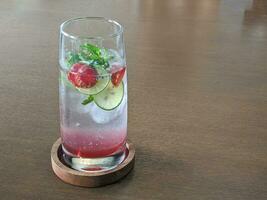 Glass of Strawberry mojito cocktail on wooden table photo