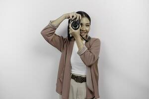 contento sonriente joven asiático mujer turista en pie con cámara tomando foto aislado en blanco estudio antecedentes