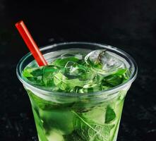 Mojito cocktail in a plastic glass with a tube photo